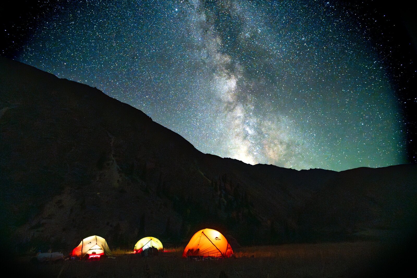 Illuminated expedition tents beneath the Milky Way in the Tian Shan.