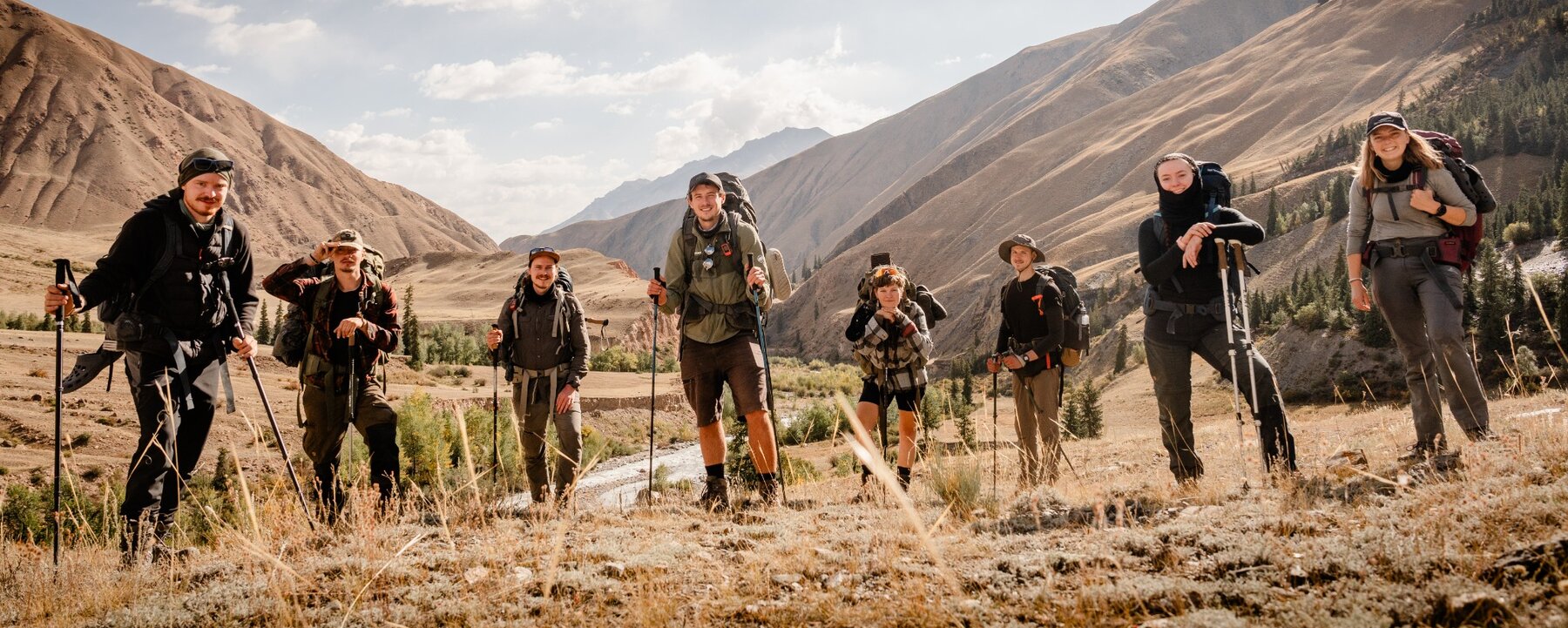 The expedition team on the trail in Kyrgyzstan; all eight faces are visible.